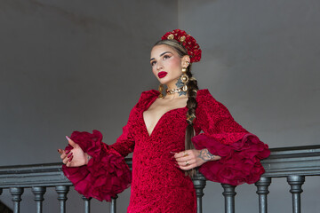 Young, beautiful, blonde woman in red flamenco dress, flowers in her hair and gold jewelry,...