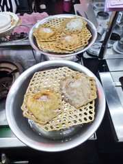 Premium bird’s nests displayed in metal bowls at a street food market. The nests are placed on woven bamboo trays with ice on top