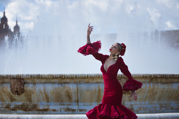 Young, beautiful, blonde woman in red flamenco dress, flowers in her hair and gold jewelry,...