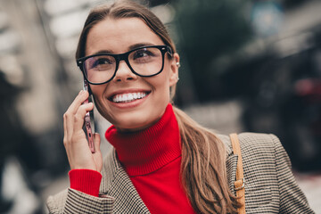 Young professional woman in stylish urban attire talking on smartphone, exuding confidence and charm