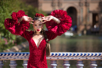 Young, beautiful, blonde woman in red flamenco dress, flowers in her hair and gold jewelry,...