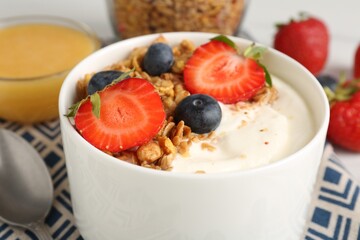 Tasty yogurt with granola, berries and honey on table, closeup