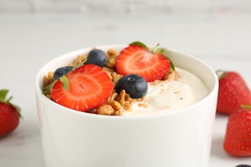 Tasty yogurt with granola and berries on white table, closeup