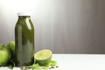 Superfood. Tasty smoothie in glass bottle and ingredients on white table, closeup. Space for text