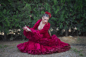Young, beautiful, blonde woman in red flamenco dress, flowers in her hair and gold jewelry,...