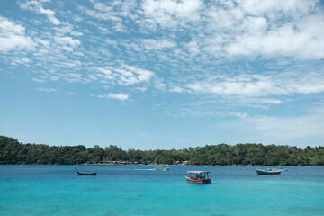 Tranquil Tropical Lagoon with Boats and Lush Greenery