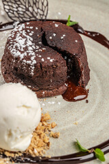 Classic chocolate lava cake with a rich molten center, dusted with powdered sugar and served with a scoop of vanilla ice cream and crumbled nuts