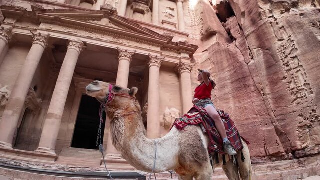 Tourist is enjoying a camel ride in front of Al Khazneh, the Treasury at Petra, a unesco world heritage site in Jordan