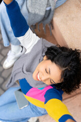 Young latin american woman relaxing on city steps with friends