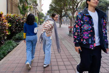 Young women looking back at a boy walking on the sidewalk
