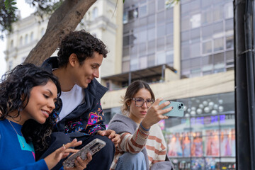 Young latin american friends enjoying urban life, taking photos and browsing social media