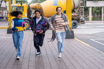 Three happy friends running and having fun in the city