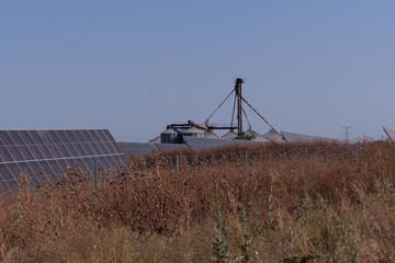 Solar panels provide sustainable energy to agricultural silos in a dry sunflower field, promoting...