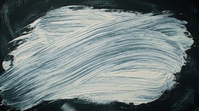 Applying white paste with a trowel on a dark surface in a close up shot view