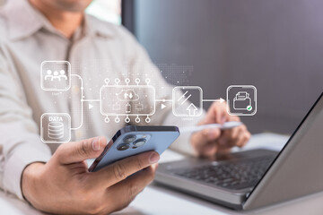 A person uses a smartphone and laptop simultaneously with digital icons representing data transfer, upload, and document sharing.