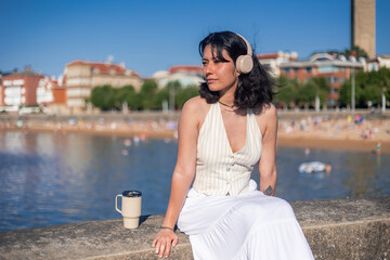 Young asian woman enjoying music and contemplating the beach