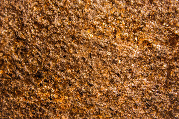 abstract textured stone surface with warm gold, brown and orange tones. slightly reflective sparkle effect with copy space background