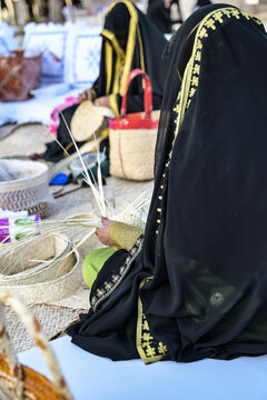 ABU DHABI, UAE - 17th November 2024: Emirati woman wearing embroidered sheila and abaiya is making hand traditional emirati embroidery during heritage festival