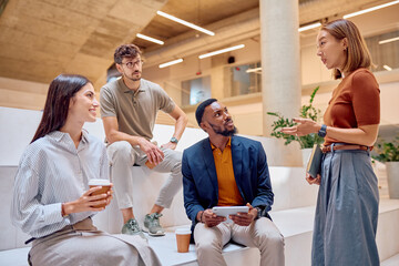 Diverse colleagues having informal meeting in modern office space, sharing ideas and discussing project progress