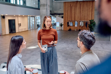 Asian businesswoman leading a meeting with her colleagues during coffee break in modern office lobby