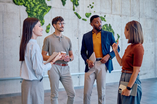 Group of diverse businesspeople discussing new project in modern office with moss wall decoration representing world map