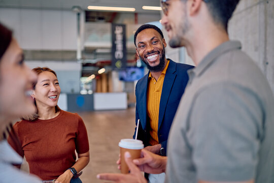Multi-ethnic colleagues enjoying a coffee break, engaging in friendly conversation and fostering teamwork in a contemporary office setting