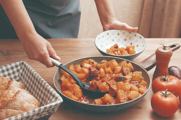 homemade stew with potatoes and meat, cooked in a frying pan, is served on a plate,