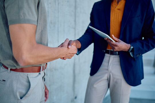 Business partners shaking hands after successful negotiation, holding tablet, closing deal, partnership and cooperation concept