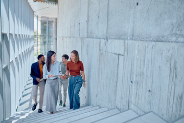 Group of multi-ethnic businesspeople discussing a project while going up the stairs in a modern office building