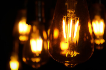 close-up of hanging light bulbs with warm, glowing filaments. bokeh effect background. warm...