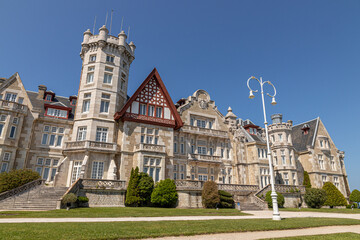 Fototapeta premium Santander, Spain. Spring view of the Palacio de la Magdalena with its grand facade, lush green lawn, and clear blue sky, once the royal summer residence of the Spanish monarchy