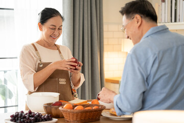 Asian senior couple cooking breakfast in the kitchen. husband helping wife on the morning weekend....