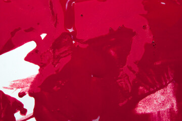 close-up of red liquid, like thick spilled paint or opaque stain substance, on a white surface with...