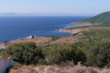 Weathered coastal scene near gibraltar strait, abandoned structure nestled among dry shrubs and verdant vegetation, revealing landscape's timeless transformation
