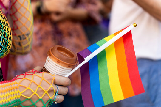 Woman holding rainbow flag and coffee at pride parade