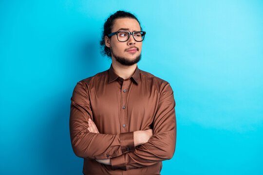 Confident young man crossing arms in casual attire standing against a vibrant turquoise background showcasing modern style