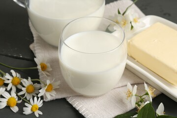 Fresh dairy products and flowers on grey wooden table, closeup