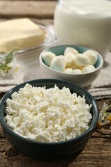 Different fresh dairy products and flowers on wooden table, closeup