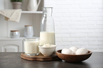 Different dairy products and eggs on gray textured table in kitchen