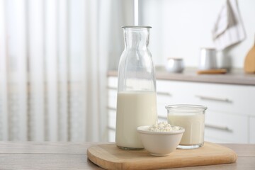 Dairy products. Fresh milk and cottage cheese on wooden table in kitchen. Space for text