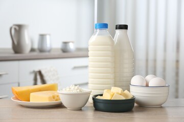 Different dairy products and eggs on wooden table in kitchen\