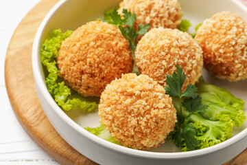 Delicious fried croquette balls with parsley and lettuce on white wooden table, closeup