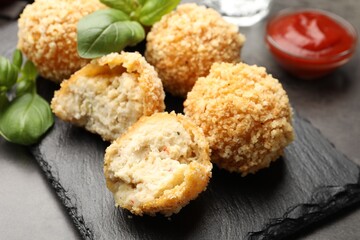 Delicious fried croquette balls with basil on grey table, closeup