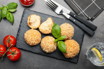 Delicious fried croquette balls with basil served on grey textured table, flat lay