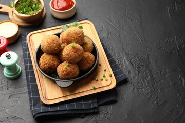 Delicious fried croquette balls with parsley and green onion on grey textured table. Space for text