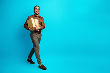 Confident young businessman holding documents, standing on a vibrant turquoise background, exuding...