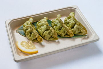 Fried Japanese gyoza dumplings filled with vibrant green vegetables, served with sweet-sour sauce, isolated on a white  background. Natural light highlights this healthy Asian street food snack.
