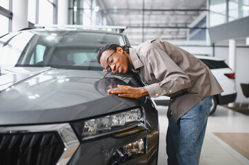 Young african american man is choosing a new vehicle in car dealership