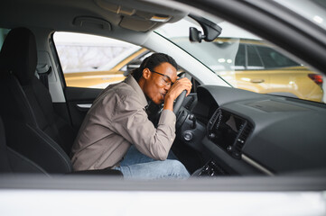 Young african american man is choosing a new vehicle in car dealership