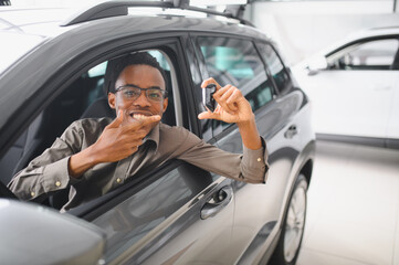 Young african american man is choosing a new vehicle in car dealership